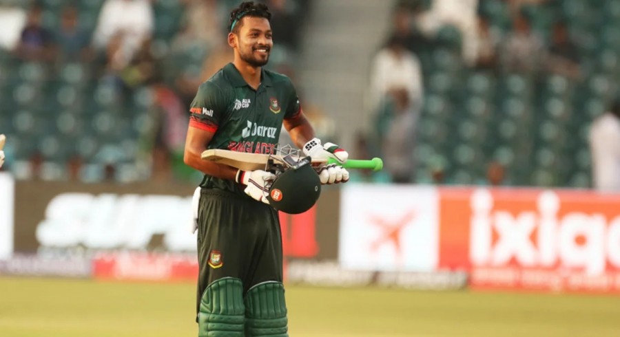 A cricketer holding a bat and a helmet